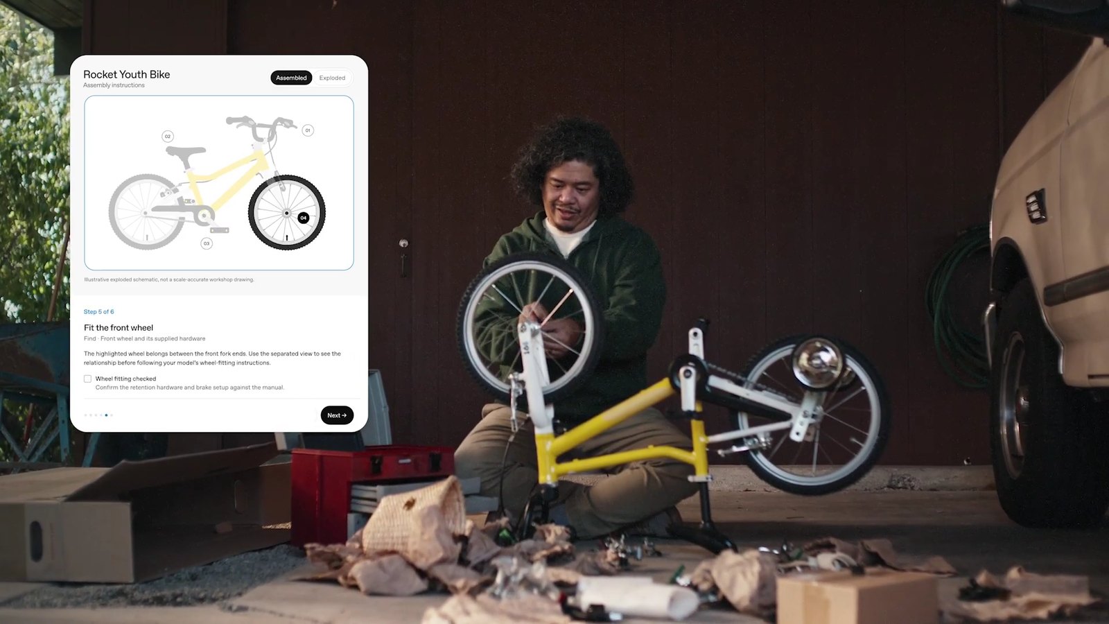 Image extraite de la vidéo de lancement d'OpenAI : une carte interactive de ChatGPT guide pas à pas le montage d'un vélo d'enfant, pendant qu'un homme fixe la roue avant.