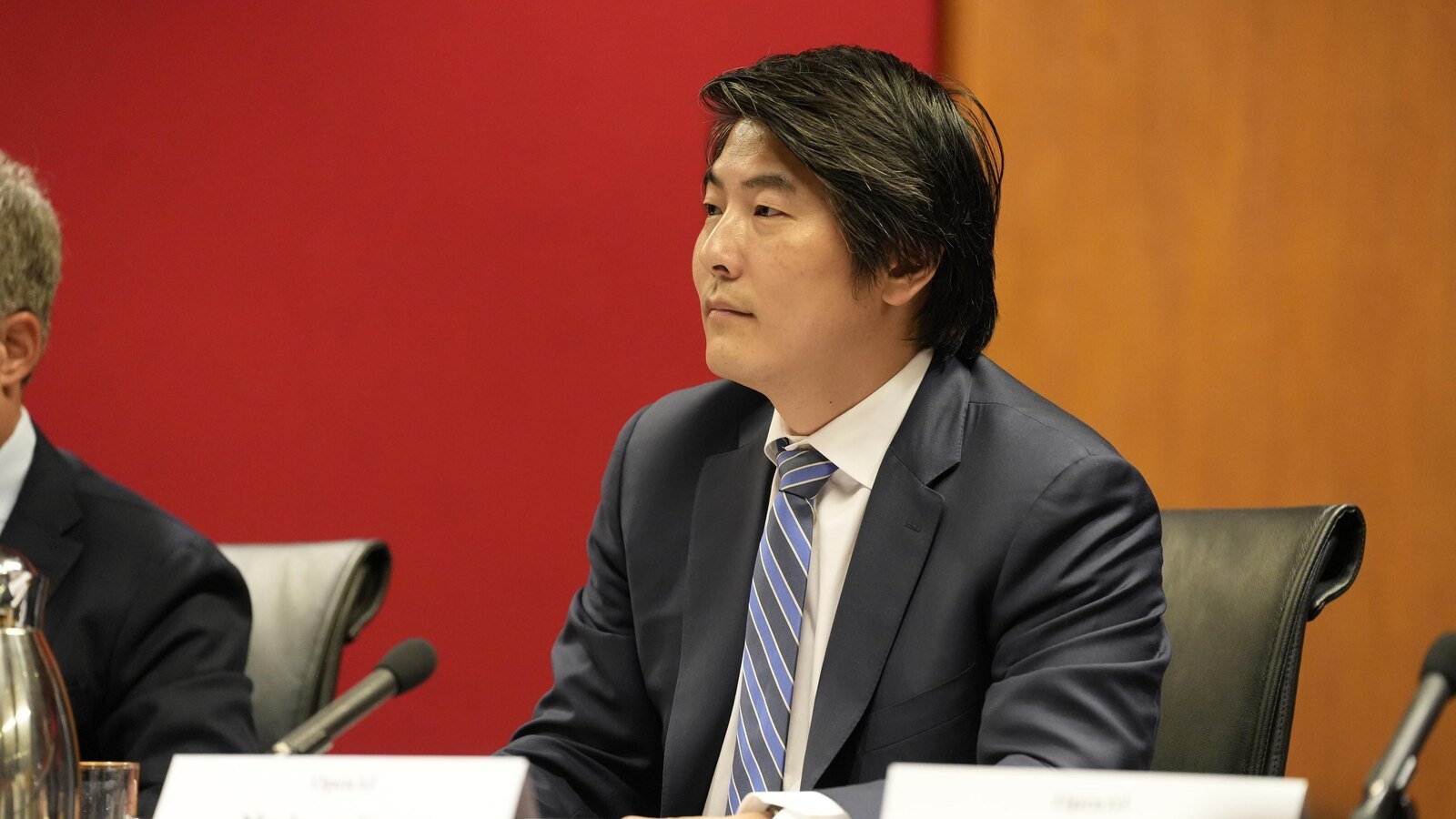 Jason Kwon assis à la table des témoins de la commission parlementaire, devant un micro.
